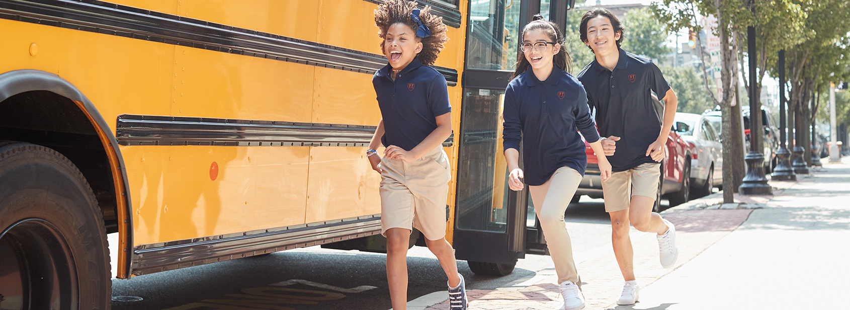 Three students running by school bus