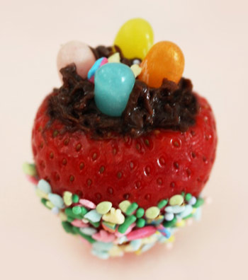 strawberry coated with chocolate and jelly beans on top and cake sprinkles at the bottom