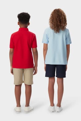 Back view of boy and girl wearing matching French Toast polo shirts in red and blue, showing shirt fit and design details. of  Short Sleeve Pique Polo