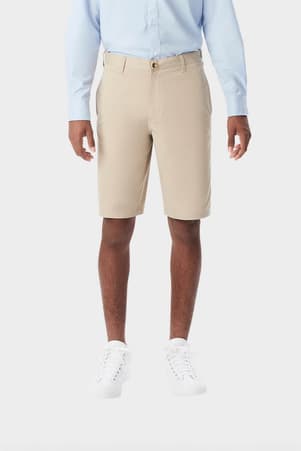 Young man wearing khaki French Toast flat front stretch twill short, front shot showing above the knee length and waistband. of  Boys' Flat Front Stretch Twill Short