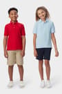 French toast pique polo shirts in red and blue worn by a boy and girl, front view showcasing a comfortable and co-ed style. of  Short Sleeve Pique Polo - 3 of 5