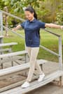 Girl in navy performance polo standing on bleachers of  Short Sleeve Performance Polo opens large image - 4 of 4