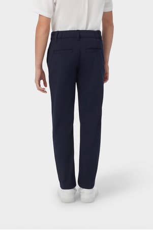 Back view of boy in navy French Toast slim fit taper leg stretch performance pant, showing slim fit and classic styling. of  Boys' Slim Fit Taper Leg Stretch Performance Pant