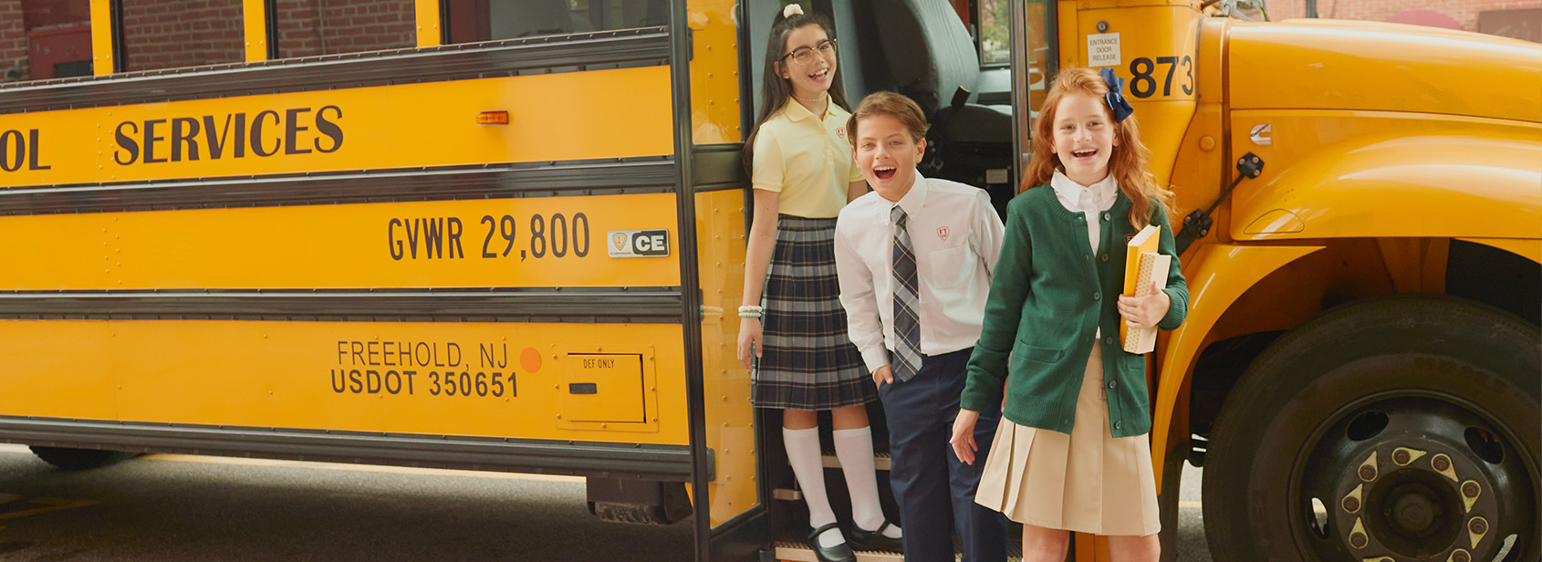 Three students in uniform getting off school bus