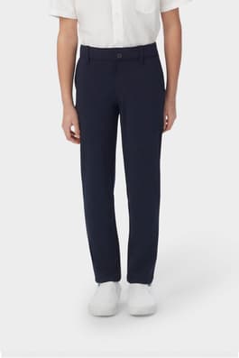 Boy wearing navy French Toast boys' slim fit taper leg stretch performance pant, front view showing moisture wicking fabric. of  Boys' Slim Fit Taper Leg Stretch Performance Pant