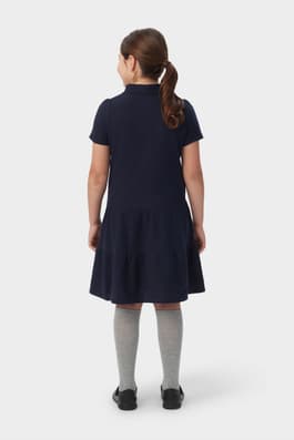 Back view of girl in navy French Toast short sleeve ruffle pique polo dress, showcasing tiered skirt detail and easy fit. of  Short Sleeve Ruffle Piqué Polo Dress
