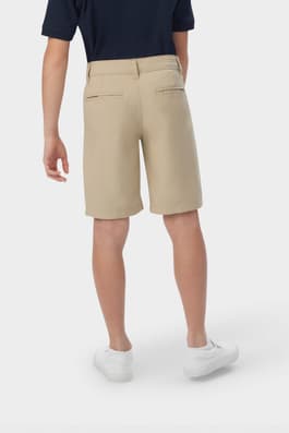 Boy wearing khaki French Toast flat front stretch performance short, back view showing waistband and pockets. of  Boys' Flat Front Stretch Performance Short