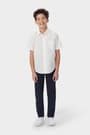 Boy wearing a white French Toast boys&#39; short sleeve oxford shirt, front view showcasing button up front and untucked length.
