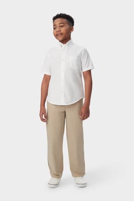 Boy wearing a white French Toast boys&#39; short sleeve oxford shirt, front view showcasing button up front and untucked length.