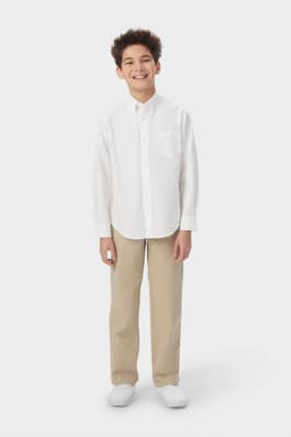 Boy wearing a white French Toast long sleeve oxford shirt, untucked to show length, button up, and classic style.