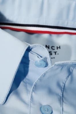 Boy wearing a white French Toast boys&#39; short sleeve dress shirt in poplin, front view showcasing crisp, classic style.