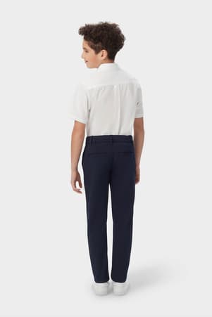 Back view of boy in navy French Toast slim fit taper leg stretch performance pant, showing slim fit and classic styling. of  Boys' Slim Fit Taper Leg Stretch Performance Pant
