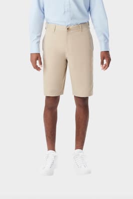 Young man wearing khaki French Toast flat front stretch twill short, front shot showing above the knee length and waistband. of  Boys' Flat Front Stretch Twill Short