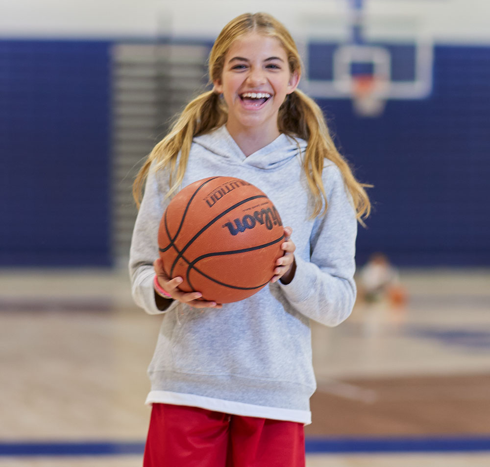 girl wearing a hoodie and holding a basketball