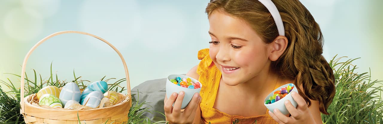Little Girl laying in grass with an open easter egg filled with jelly beans, with text Perfect Spring Treats