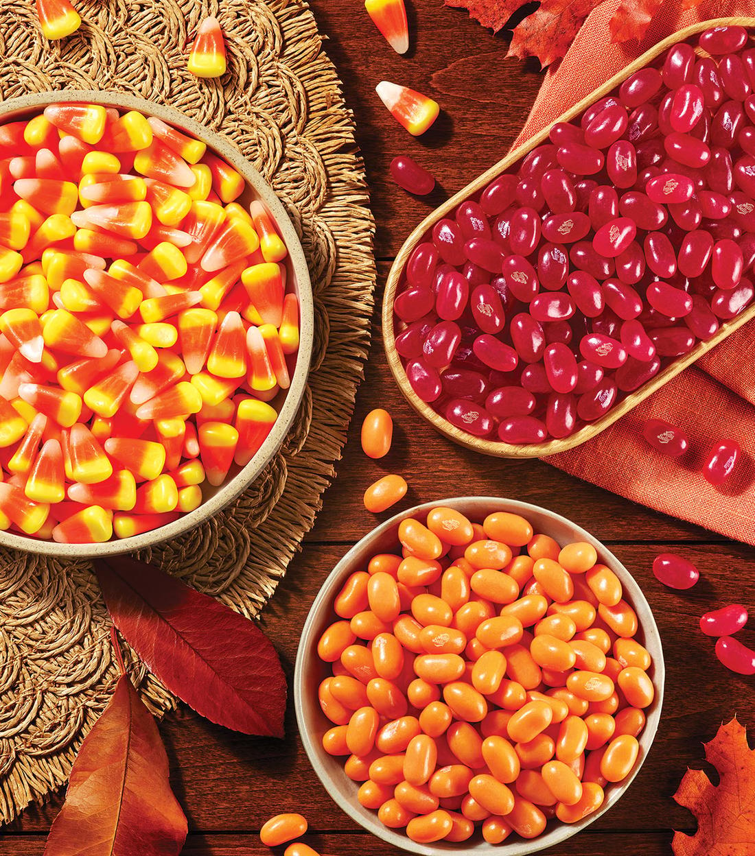 Bowls filled with Candy Corn, Orange and red Jelly Beans on a brown table